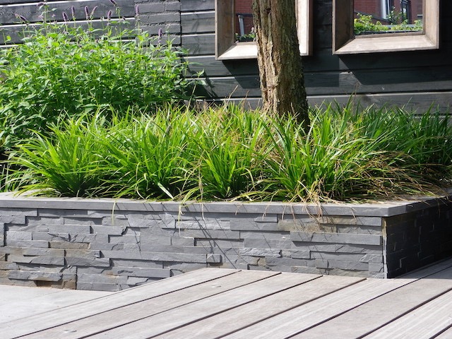 Moderne patiotuin met natuursteen tegels en verhoogde vlonder